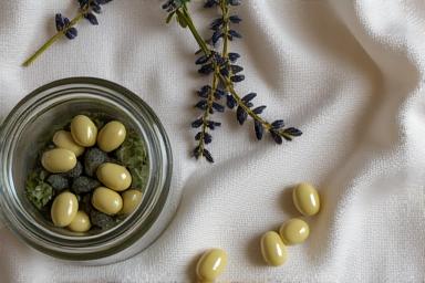 Delikatne kapsułki z suplementami diety na sen (magnez, melatonina) na tle ziół leczniczych.